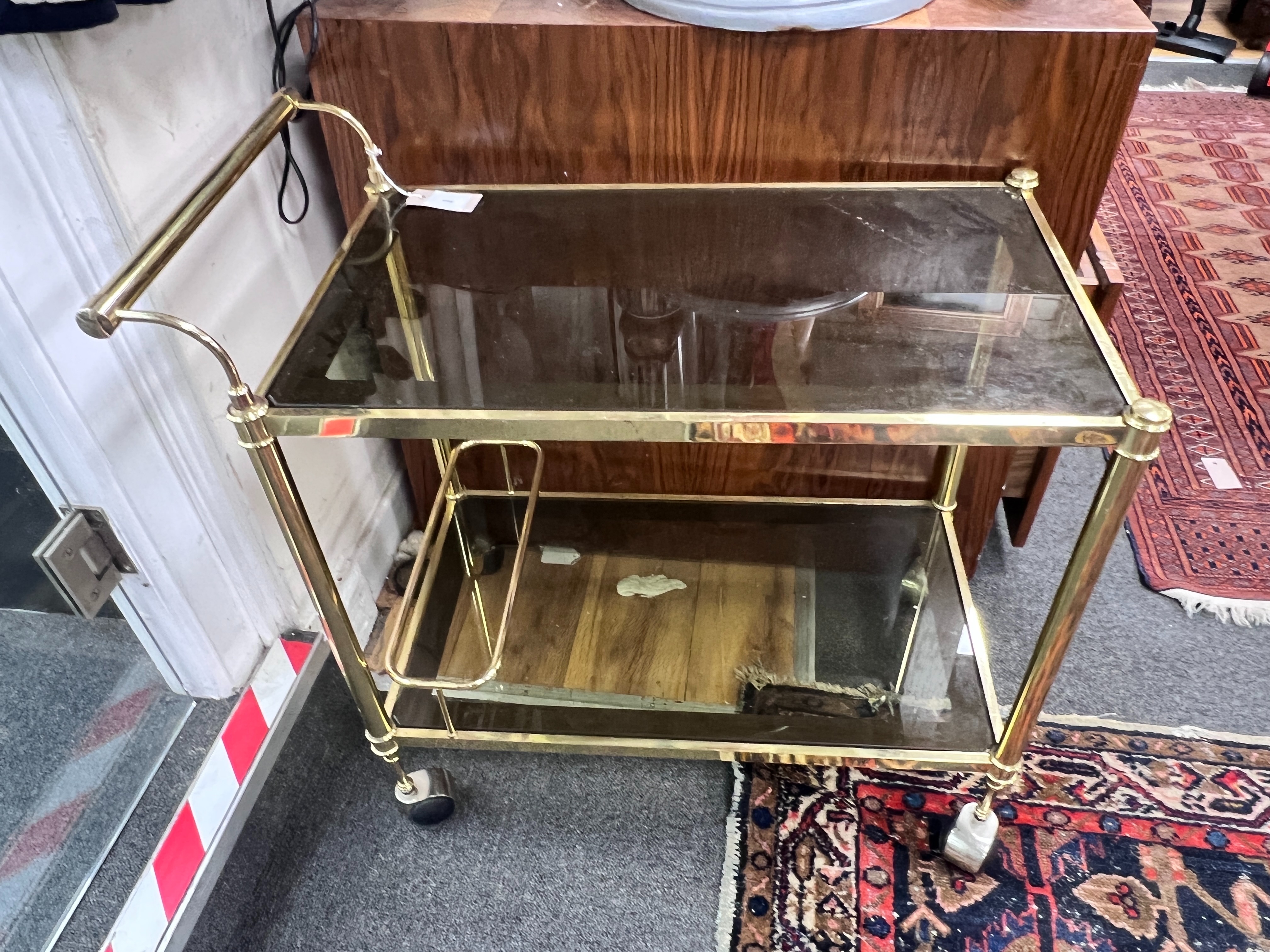 A French gilt metal smoked glass two tier trolley, width 74cm, depth 40cm, height 70cm